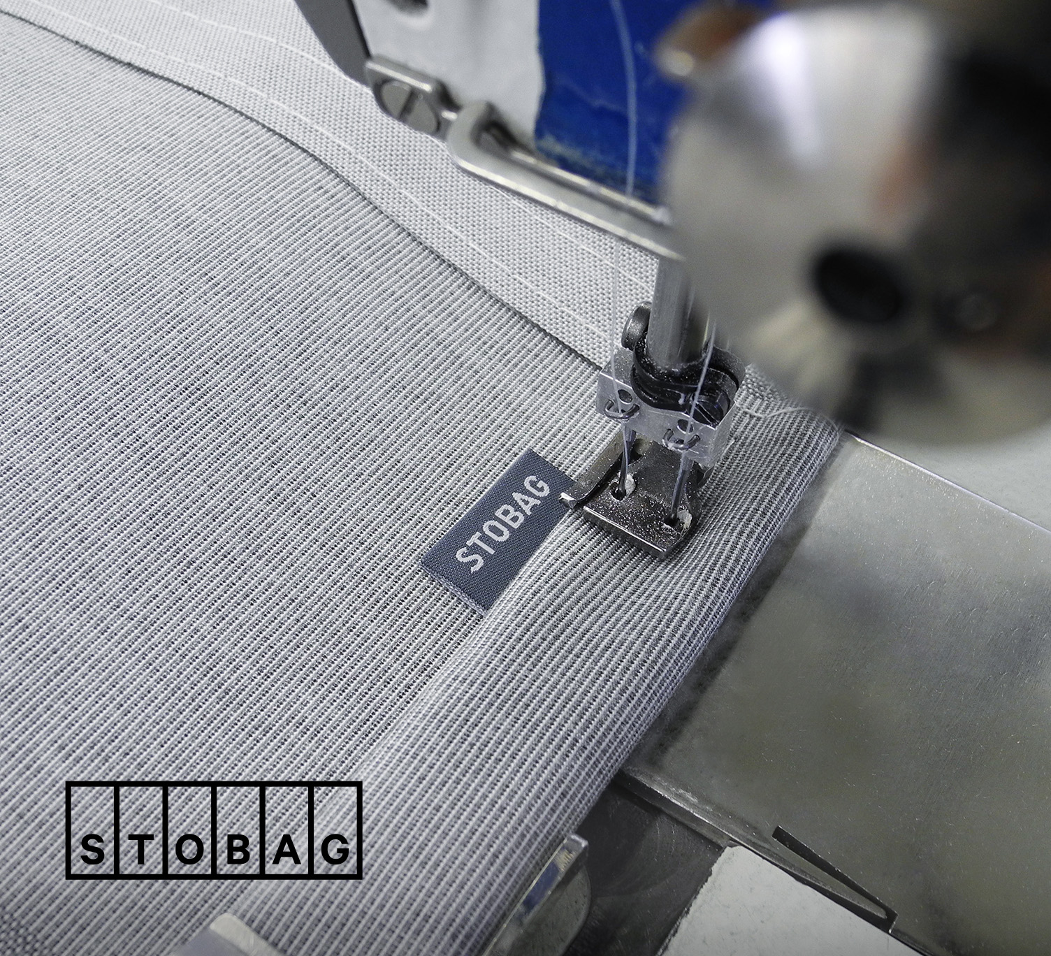 Detailaufnahme einer Nähmaschine, die ein STOBAG-Label auf einen hochwertigen Markisenstoff näht.