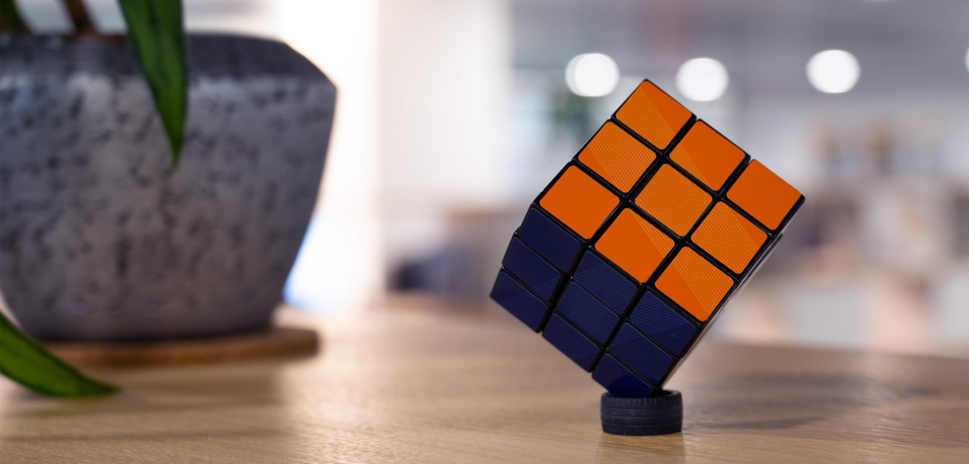 Rubik’s Cube in Schräglage auf einem Tisch, mit orange-schwarzer Farbseite im Fokus