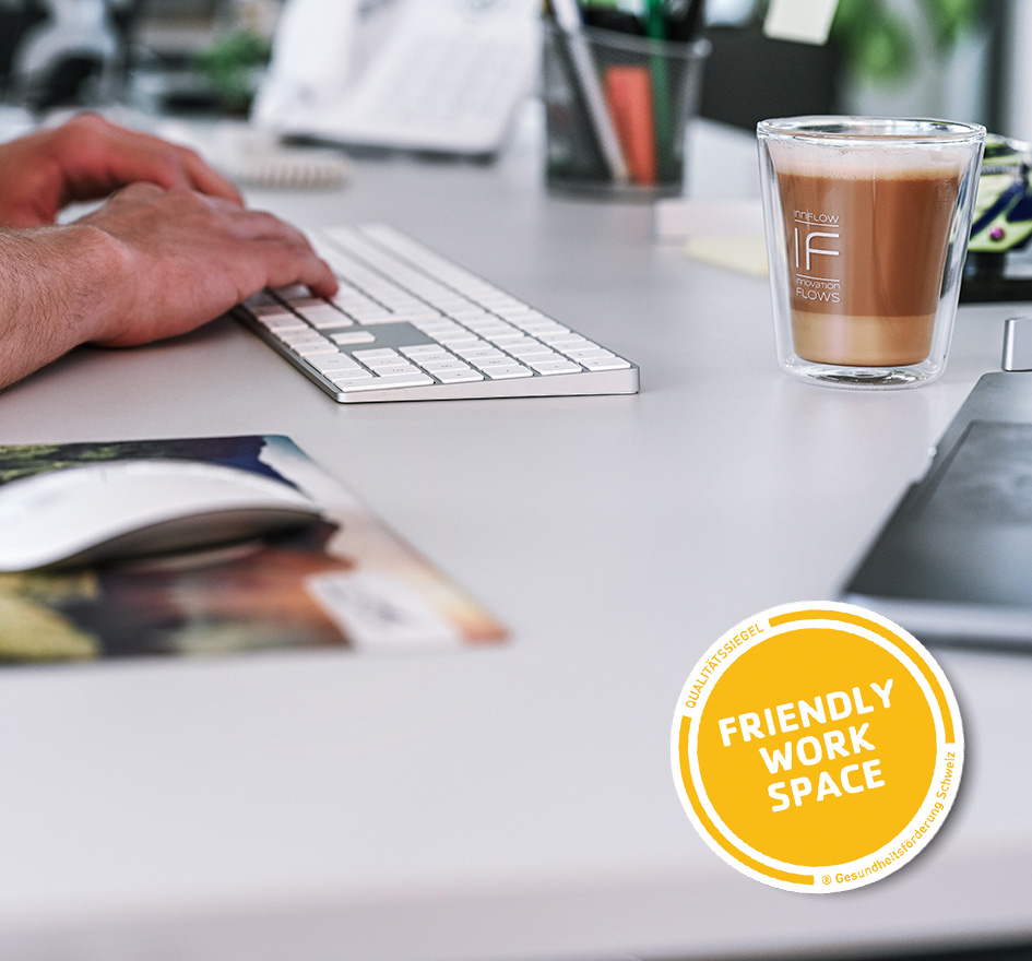 Mann tippt auf Tastatur etwas ein, daneben steht ein Kaffee – symbolisiert moderne Arbeitsumgebung und Infrastruktur