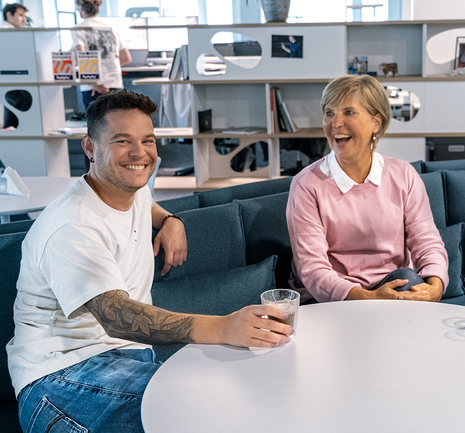 Zwei Innflow Mitarbeitende sitzen am Tisch und unterhalten sich fröhlich