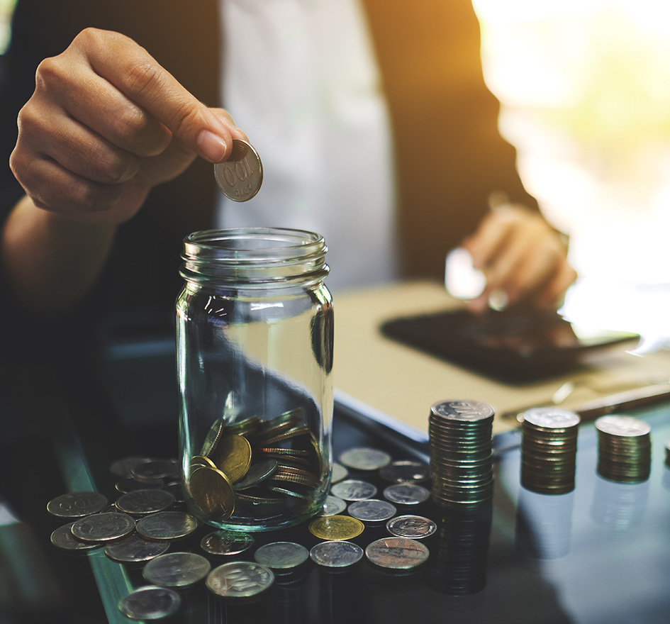 Hand wirft eine Münze in ein Glas, das mit weiteren Münzen gefüllt ist – symbolisiert hohe einmalige Investitionen und gebundenes Kapital für IT-Infrastruktur.