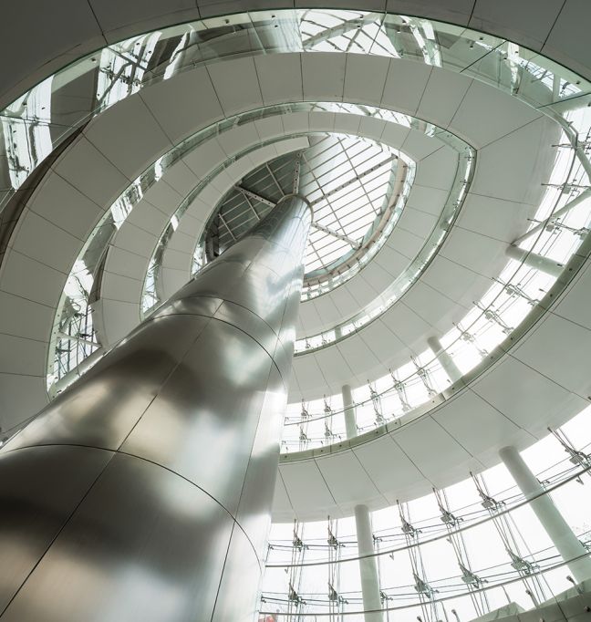Innenaufnahme eines futuristischen Gebäudes mit zentralem Pfeiler und umlaufenden Galerien – steht für zentrale, cloudbasierte Integrationslösungen.