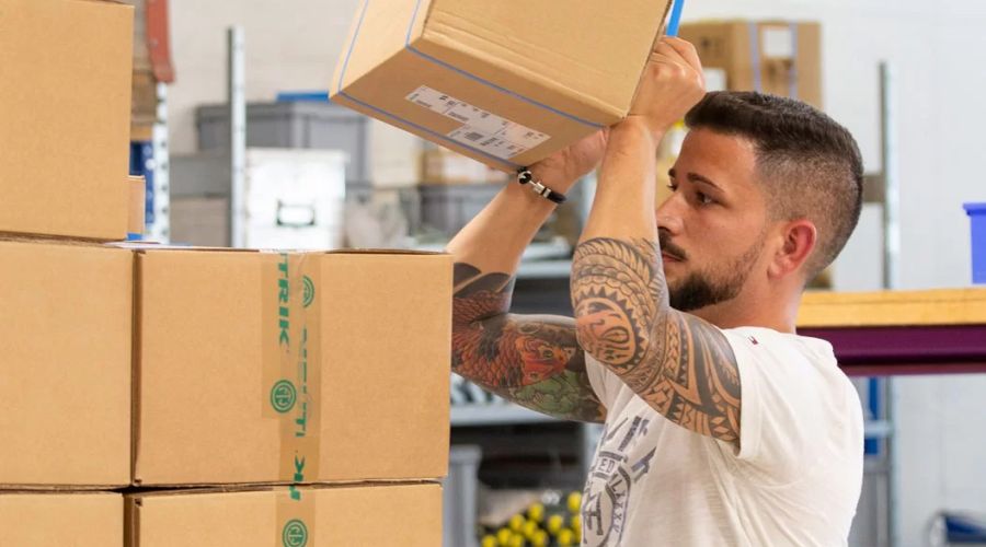 Mitarbeiter bei Neutrik stapelt Kartons in einem Lager